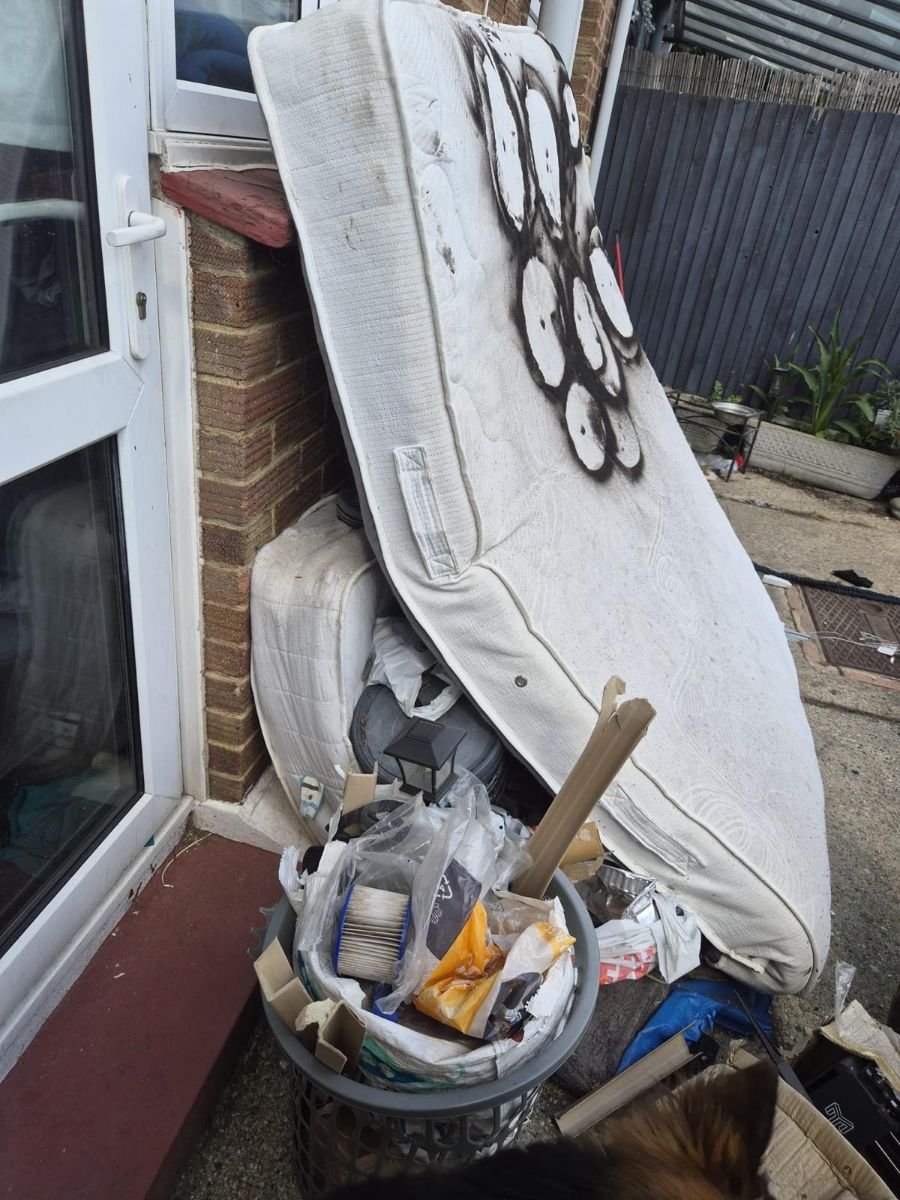 Fire-damaged mattress and household rubbish left outside a property awaiting removal